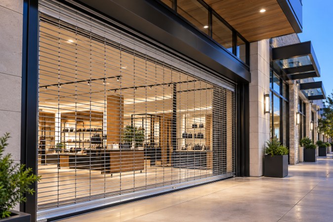 Open rolling security grille closed across a modern retail storefront